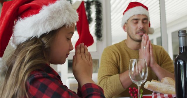 Focused caucasian daughter and father praying together before christmas dinner - Download Free Stock Photos Pikwizard.com