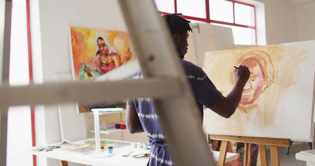 Rear view of african american male artist wearing apron painting on canvas at art studio - Download Free Stock Photos Pikwizard.com
