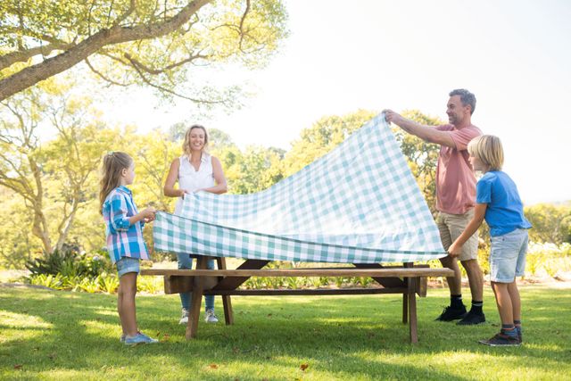 Family spreading the tablecloth on picnic table - Download Free Stock Photos Pikwizard.com