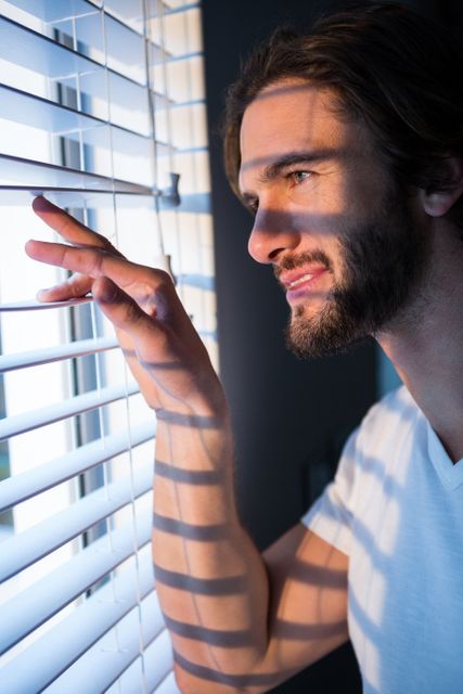 Man looking through window blinds after waking up - Download Free Stock Photos Pikwizard.com