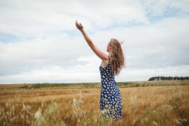 Rear view woman standing with arms outstretched in field