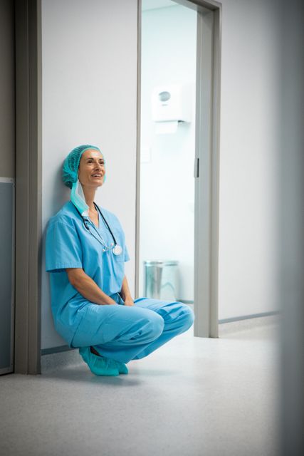 Happy caucasian female doctor wearing stethoscope sitting in hospital corridor - Download Free Stock Photos Pikwizard.com