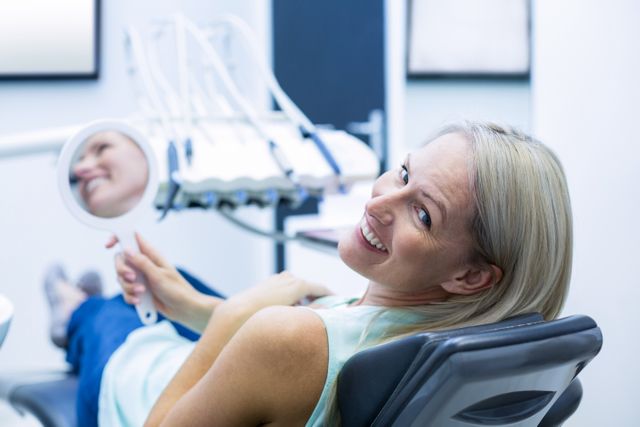 Female patient smiling while holding mirror - Download Free Stock Photos Pikwizard.com