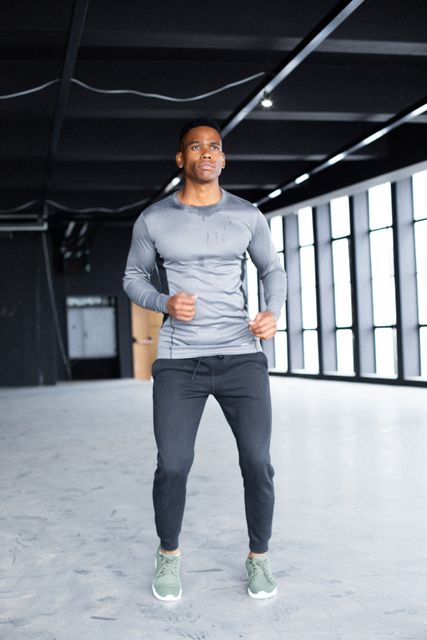 African american man wearing sports clothes and jogging in empty building - Download Free Stock Photos Pikwizard.com