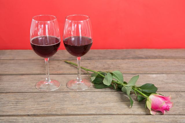 Two red wine glasses and pink rose - Download Free Stock Photos Pikwizard.com