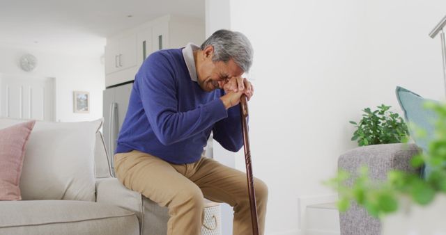 Image of tired, sad senior biracial man sitting and leaning head on walking stick - Download Free Stock Photos Pikwizard.com