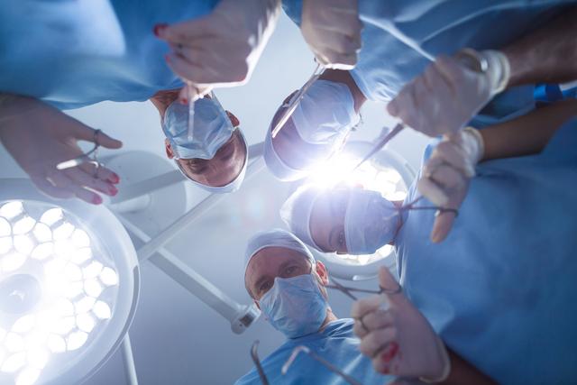 Group of surgeons performing operation in operation room at hospital