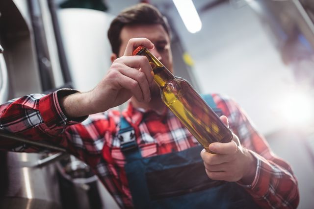 Manufacturer examining beer bottle at brewery - Download Free Stock Photos Pikwizard.com