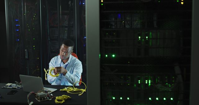 African american male computer technician laptop working in business server room. digital information storage and communication network technology.