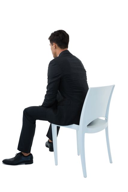Rear view of businessman sitting on chair against white background