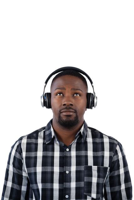 Thoughtful man listening to music on headphones against white background