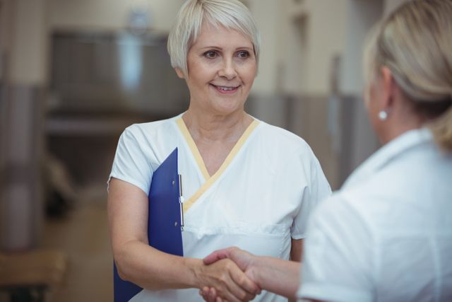 Two nurse shaking hands in corridor - Download Free Stock Photos Pikwizard.com