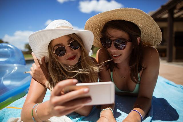 Women taking selfie on mobile phone while sunbathing - Download Free Stock Photos Pikwizard.com