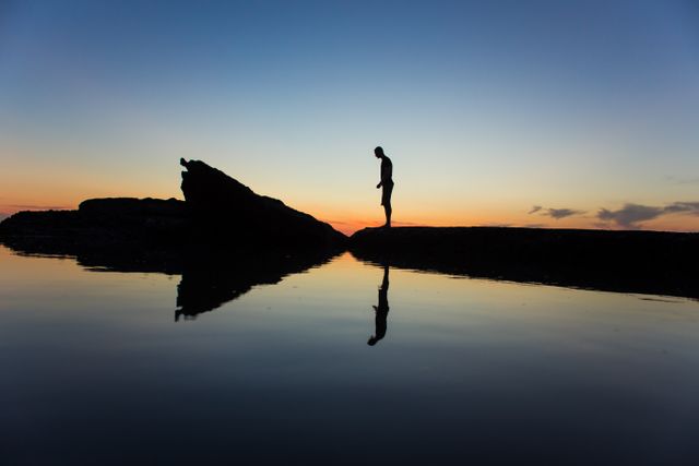 Silhouette of Man Standing Near Body of Water during Yellow Sunset - Download Free Stock Photos Pikwizard.com