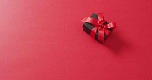 Black gift box with red ribbon on red background with copy space - Download Free Stock Photos Pikwizard.com