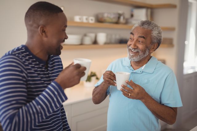 Smiling father and son interacting while having cup of coffee - Download Free Stock Photos Pikwizard.com