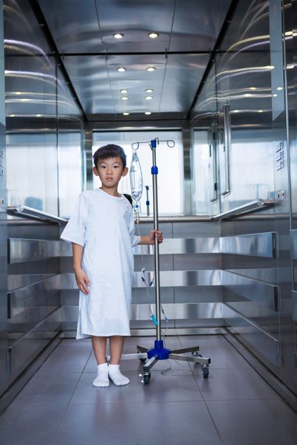 Smiling boy patient holding intravenous iv drip stand in lift - Download Free Stock Photos Pikwizard.com