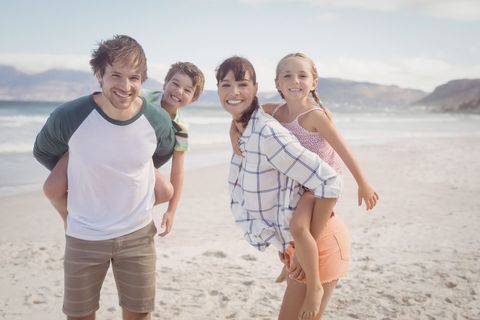 Portrait of young parents piggybacking their children - Download Free Stock Photos Pikwizard.com