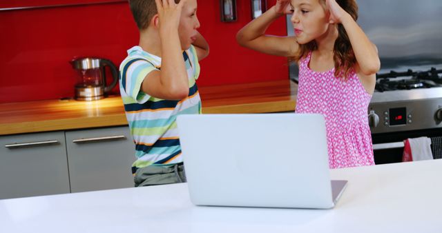 Two children exhibit frustration over a computer issue in the kitchen. - Download Free Stock Photos Pikwizard.com