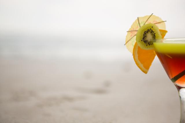 Glass of cocktail drink garnished with kiwi, lime and cocktail umbrella - Download Free Stock Photos Pikwizard.com