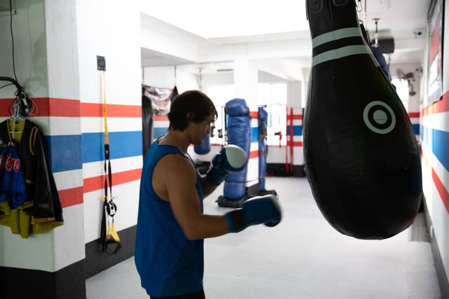 Mixed race man exercising with punching bag in boxing gym - Download Free Stock Photos Pikwizard.com