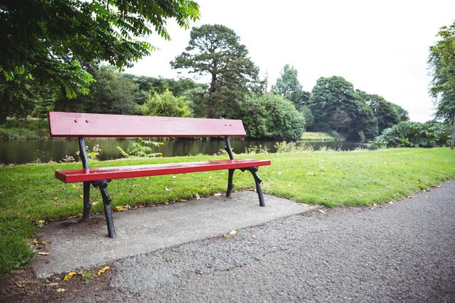 Empty red wooden bench at lakeside, backgrounds