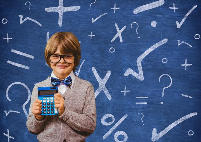 Happy schoolboy holding calculator in front of a chalkboard