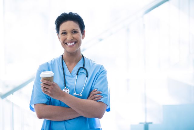 Female nurse standing with disposable cup in corridor - Download Free Stock Photos Pikwizard.com