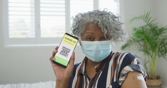 African american senior woman wearing face mask showing covid vaccinate passport. senior health and lifestyle during covid 19 pandemic.