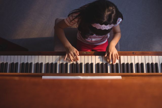 Overhead view of elementary girl playing piano in classroom at music school