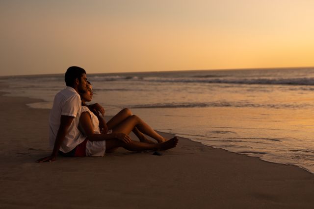Young couple looking at sea on the beach during sunset