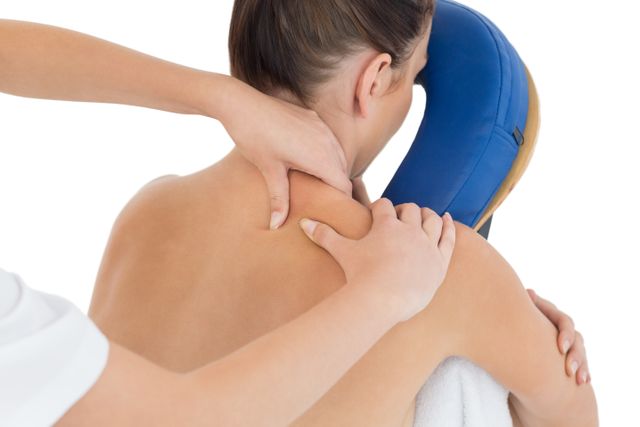 Cropped image of masseuse giving back massage to naked woman against white background