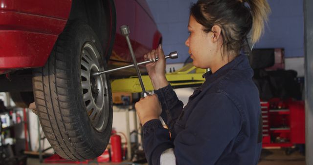 Female mechanic changing tires of the car using a wheel wrench at a car service station - Download Free Stock Photos Pikwizard.com