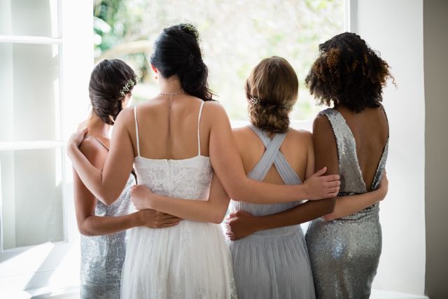 Rear view of bride and bridesmaids standing together near window - Download Free Stock Photos Pikwizard.com