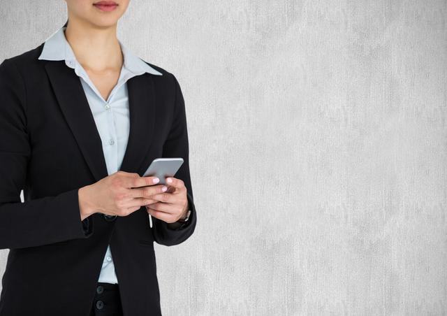 Midsection of businesswoman holding smart phone against wall - Download Free Stock Photos Pikwizard.com