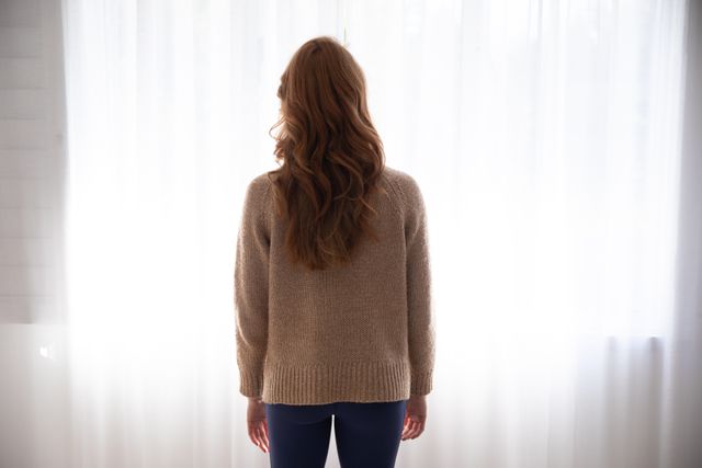Rear view of woman standing near the window curtains at home - Download Free Stock Photos Pikwizard.com