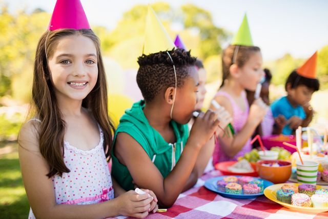 Close up of cute girl smiling in front of other children during a birthday party - Download Free Stock Photos Pikwizard.com