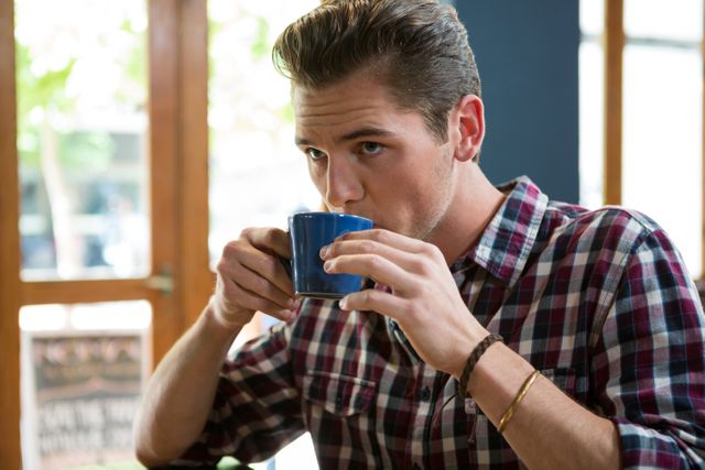 Handsome man drinking coffee in cafeteria - Download Free Stock Photos Pikwizard.com
