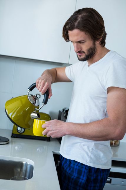 Man pouring coffee into cup in kitchen at home