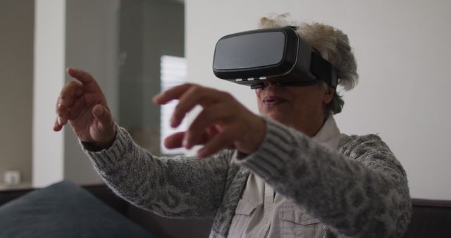 African american senior woman gesturing while wearing vr headset at home. retirement senior lifestyle living in quarantine lockdown concept