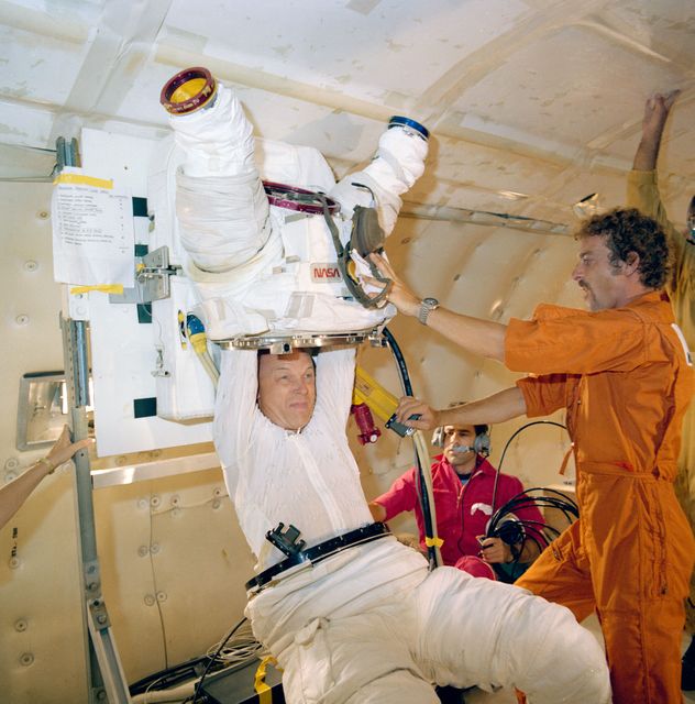 S82-33603 (November 1982) --- Astronaut F. Story Musgrave, STS-6 mission specialist, is assisted in a suit donning and doffing exercise in the weightlessness provided by a KC-135 ?zero-gravity? aircraft. Dr. Musgrave and the next mission?s other mission specialist, astronaut Donald H. Peterson, participated in the donning and doffing as a simulation for their preparations aboard the Challenger when they are called upon to perform an extravehicular activity (EVA) which was postponed from NASA?s first operational STS flight earlier this month. The suit is called an Extravehicular Mobility Unit (EMU). Photo credit: NASA