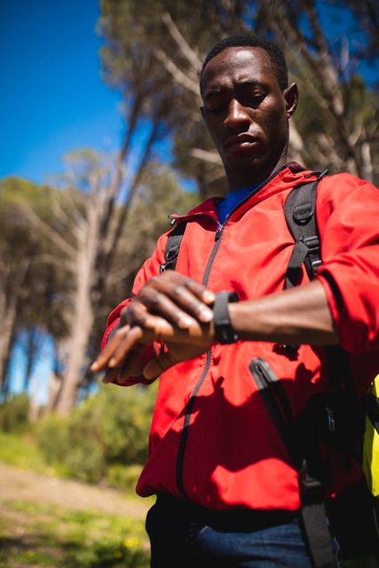 African american man using smartwatch while trekking in the forest - Download Free Stock Photos Pikwizard.com