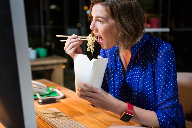 Businesswoman eating noodles at her desk - Download Free Stock Photos Pikwizard.com