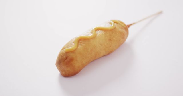 Image of corn dog with mustard on a white surface. food, cuisine and catering ingredients.