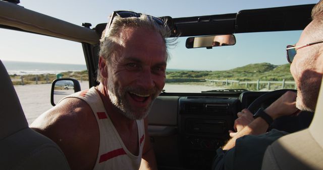 Happy caucasian gay male couple driving car and smiling on sunny day at the beach. summer road trip and holiday in nature.
