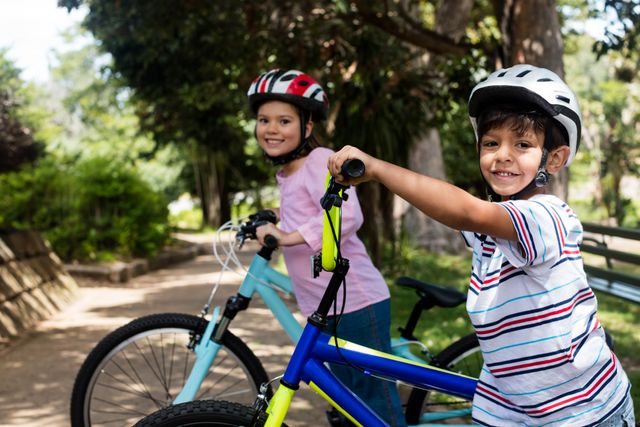 Portrait of smiling children standing with bicycle in park - Download Free Stock Photos Pikwizard.com