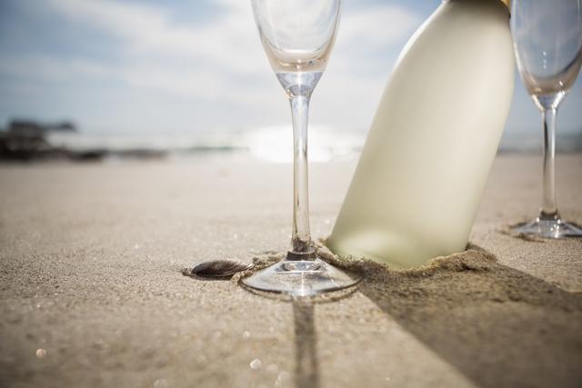 Close-up of champagne bottle and two glasses on sand - Download Free Stock Photos Pikwizard.com