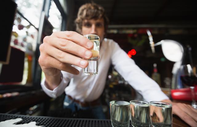 Portrait of bartender holding tequila shot glass at bar counter - Download Free Stock Photos Pikwizard.com