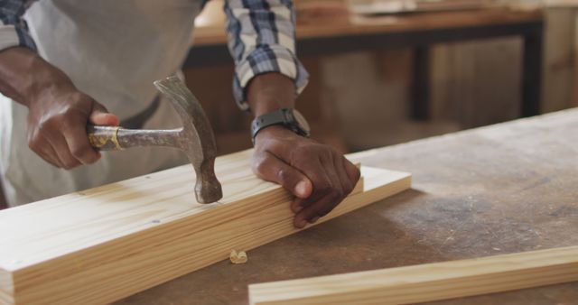 Mid section of african american male carpenter hammering nails into the wood at a carpentry shop - Download Free Stock Photos Pikwizard.com