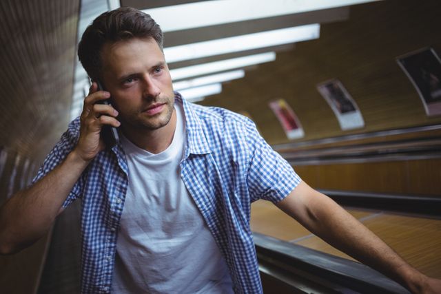 Handsome man talking on mobile phone on escalator at railway platform